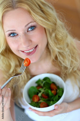 Photo: Beautiful blond woman eating fresh salad Beautiful blond woman eating fresh salad