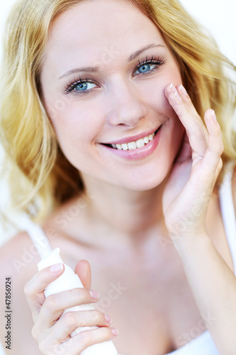 Photo: Portrait of beautiful woman applying moisturizer Portrait of beautiful woman applying moisturizer