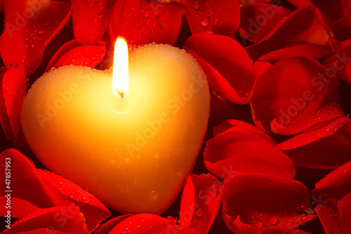 Photo: Heart shape candle and rose petals Heart shape candle and rose petals