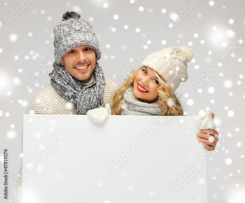 Photo: couple in a winter clothes holding blank board couple in a winter clothes holding blank board