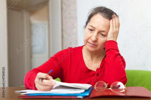Photo: Sad mature woman reads documents Sad mature woman reads documents