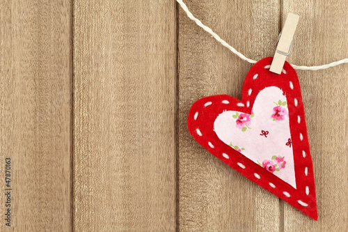 Photo: Red handmade felt heart clipped with clothespin on wood Red handmade felt heart clipped with clothespin on wood