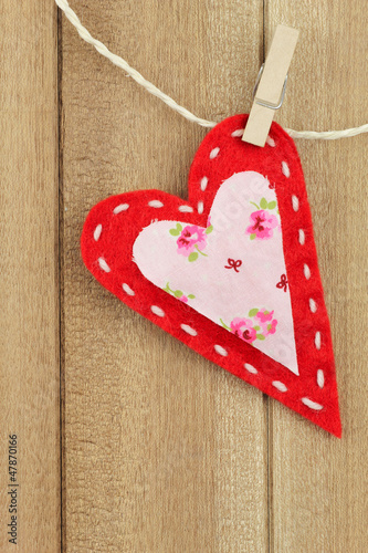 Photo: Red handmade felt heart clipped with clothespin on wood Red handmade felt heart clipped with clothespin on wood
