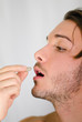 Photo: Handsome young man taking pill or medicine capsule Handsome young man taking pill or medicine capsule