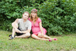 a happy young pregnant woman with her husband resting in a park