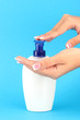 woman squeezing lotion on her hand, on blue background close-up