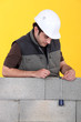 A mason using a plumb bob to check his wall.