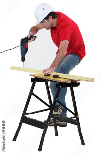 Photo: Carpenter drilling into wooden plank Carpenter drilling into wooden plank