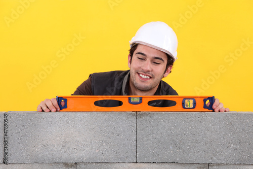 Photo: Up-beat mason using spirit-level on wall Up-beat mason using spirit-level on wall