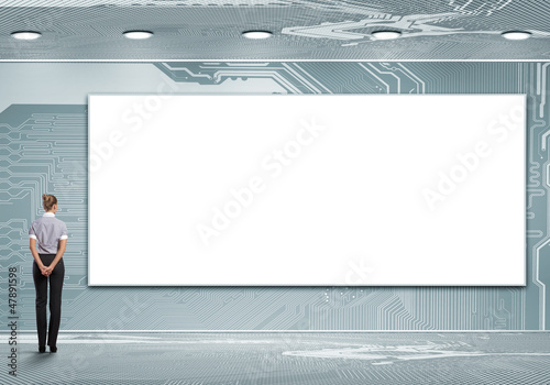 Photo: Business person standing near a blank billboard Business person standing near a blank billboard