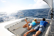 Couple relaxing on catamaran net looking at the sea