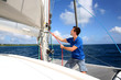 Young man lifting the sail of catamaran during cruising