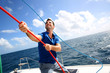 Young man lifting the sail of catamaran during cruising