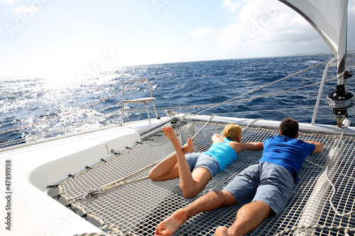Photo: Couple relaxing on catamaran net looking at the sea Couple relaxing on catamaran net looking at the sea