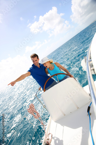 Photo: Young couple navigating on a yacht in caribbean sea Young couple navigating on a yacht in caribbean sea