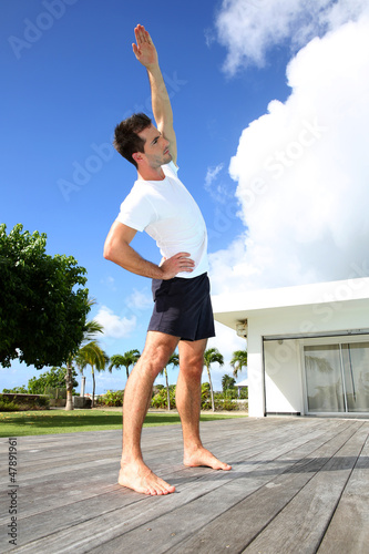 Photo: Young man doing stretching exercises by the pool Young man doing stretching exercises by the pool