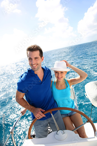 Photo: Young couple navigating on a yacht in caribbean sea Young couple navigating on a yacht in caribbean sea