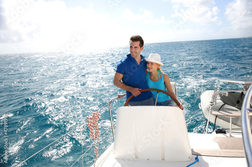Photo: Young couple navigating on a yacht in caribbean sea Young couple navigating on a yacht in caribbean sea