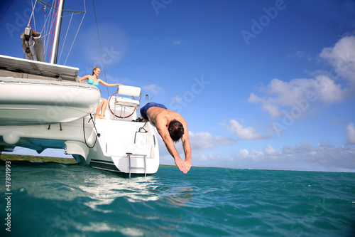 Photo: Man diving from catamaran deck into the sea Man diving from catamaran deck into the sea