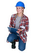 Female construction worker kneeling with clip-board