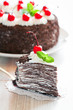 Piece of chocolate crepe cake with whipped cream and cherries