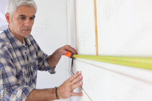 Photo: Man measuring wall Man measuring wall