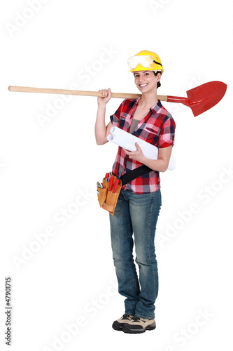 Photo: Female construction worker holding plans and spade Female construction worker holding plans and spade