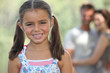 Foto: portrait of jovial little girl with parents in background portrait of jovial little girl with parents in background
