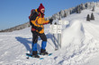 Schneeschuhwanderin vor tief verschneitem Wegweiser.
