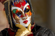 Person in Venetian costume attends Carnival of Venice.