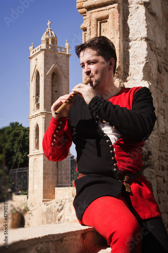 Photo: Man in a medieval suit plays a flute Man in a medieval suit plays a flute