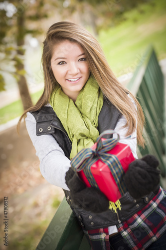 Photo: Pretty Woman with Wrapped Gift with Bow Outside Pretty Woman with Wrapped Gift with Bow Outside