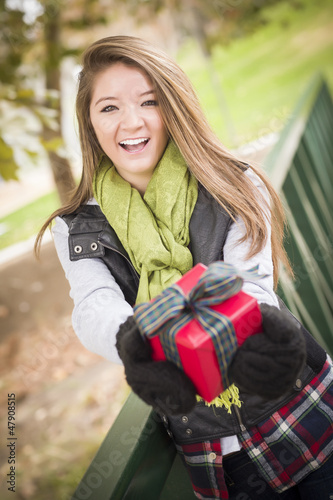 Photo: Pretty Woman with Wrapped Gift with Bow Outside Pretty Woman with Wrapped Gift with Bow Outside