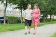 a happy young pregnant woman with her husband walking in a park