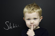 Smart young boy stood infront of a blackboard