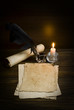 feather, old paper and candle on a wooden background