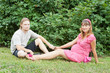 a happy young pregnant woman with her husband resting in a park