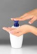 woman squeezing lotion on her hand, on grey background close-up