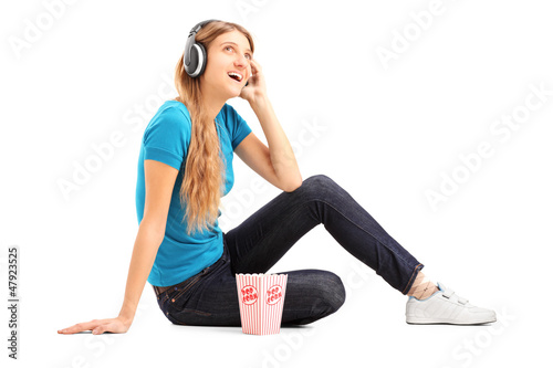 Photo: Blond female listening a music and eating popcorn Blond female listening a music and eating popcorn