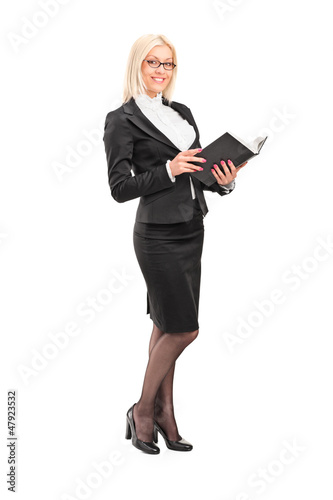 Photo: Full length portrait of a blond female teacher holding a book Full length portrait of a blond female teacher holding a book