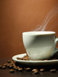 cup of coffee with beans on table, on brown background