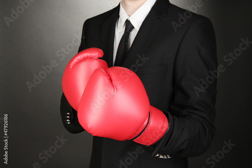 Photo: Businessman in boxing gloves on grey background Businessman in boxing gloves on grey background