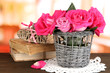 Beautiful pink roses in vase on wooden table on room background