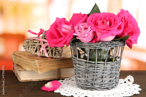 Photo: Beautiful pink roses in vase on wooden table on room background Beautiful pink roses in vase on wooden table on room background