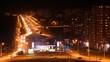 Workers lay down asphalt opposite to gasoline station at night