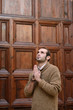 Man praying in front of the church holding prayer beads