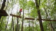 girl walks on suspended by cables on trees in wood to boards