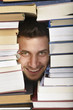 Photo: Student looking between stacked books Student looking between stacked books