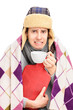 Sick guy covered with blanket holding a hot-water bottle and dri