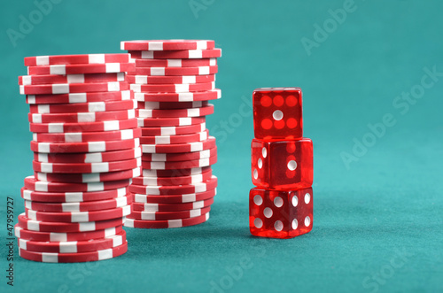 Photo: Red poker gambling chips on a green playing table Red poker gambling chips on a green playing table